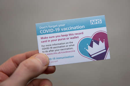 OXFORD, UK - February 2020: A person holds an NHS Covid-19 vaccination reminder
