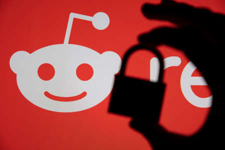 LONDON, UK - February 2021: Silhouette of padlock against Reddit logo
