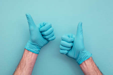 Doctors hand wearing protective surgical gloves giving thumbs up sign.の写真素材