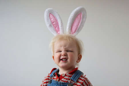 A cute toddler wearing easter bunny ears making a silly smiling faceの写真素材