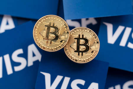 LONDON, UK - March 2021: Bitcoin cryptocurrency on Visa financial service logo