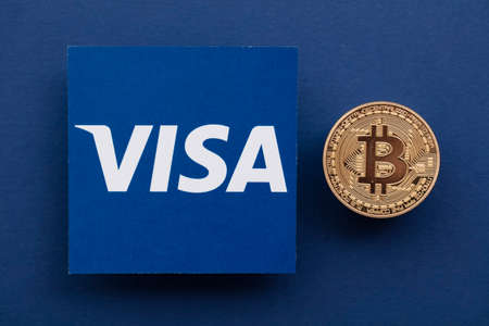 LONDON, UK - March 2021: Bitcoin cryptocurrency on Visa financial service logo