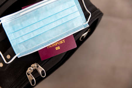 travel. Suitcase with a protective face mask and passportの写真素材