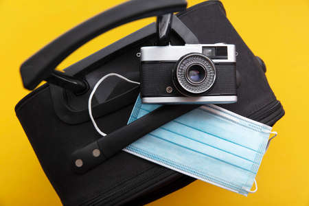 Covid travel. Luggage packed with a face mask and vintage cameraの写真素材