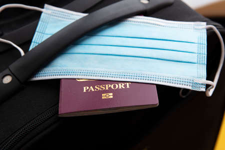 Covid travel. Luggage packed with a face mask and passport