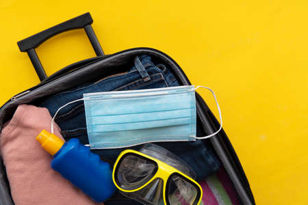 Suitcase packed for a summer vacation during the coronavirus global pandemicの写真素材