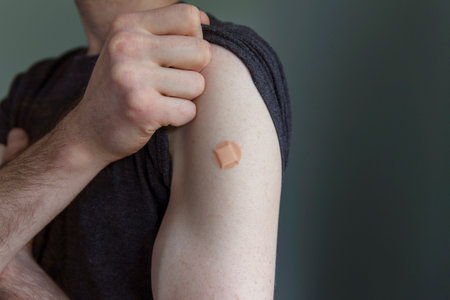 Caucasian man with a plaster on their arm after a vaccination injection