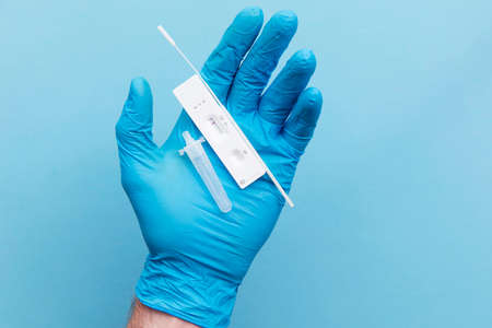 Doctor in blue gloves using a lateral flow covid-19 testing kit