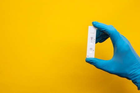 Person wearing blue gloves holding a coronavirus lateral flow testの写真素材