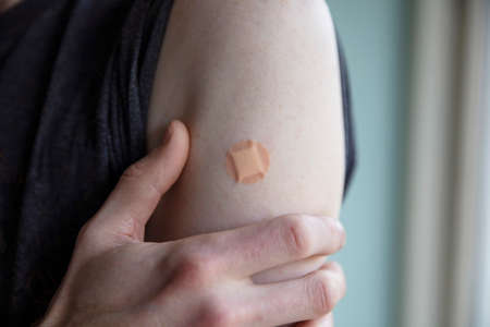 Caucasian man with a plaster on their arm after a vaccination injectionの写真素材