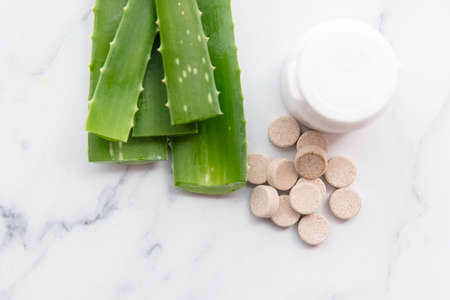Aloe vera natural tablets. Freshly cut leaves with a pill bottle and tabletsの写真素材