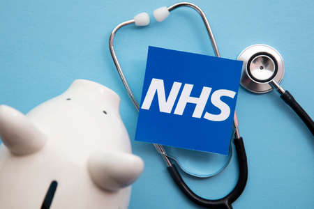 LONDON, UK - July 2021: NHS National health service logo with saving piggy bankのeditorial素材