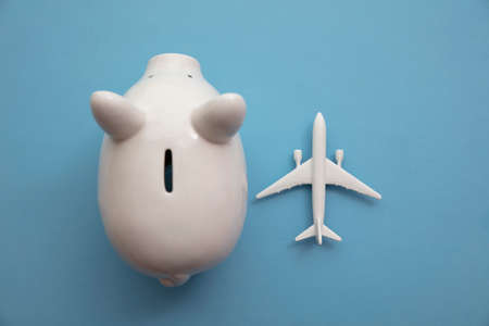 Holiday flight fare saving concept. Piggy bank with a toy plane. Vacation budget planningの写真素材