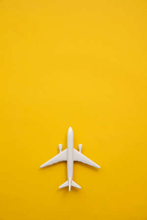 White passenger airplane on a summer yellow background. Travel and vacation background
