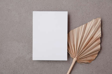 Blank invitation card for a natural wedding or celebration event with dried palm leaf stemの写真素材