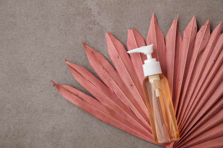 Natural beauty product background with a bottle and dried pink palm leavesの写真素材