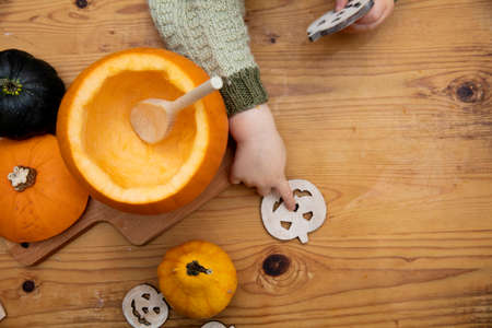 Overhead view of a toddlers hands playing with a pumpkin whilst making a lantern decoration for halloweenの写真素材