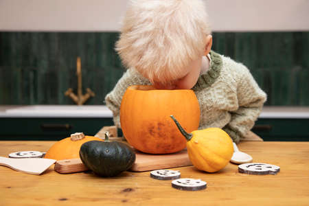 A cute young boy peering into a halloween pumpkin whilst making a lantern decorationの写真素材