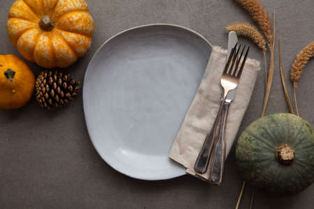 Overhead autumn thanksgiving dinner place setting with pumpkins cutlery and an empty plate