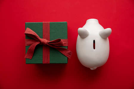 Festive Christmas financial savings concept. White piggy bank money box with presents