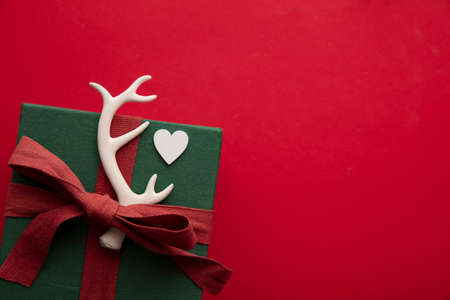 Hand made stylish Christmas gift box present. Box tied with red ribbon and a festive reindeer antlerの写真素材