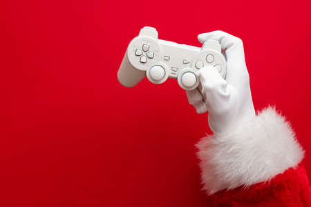 Father Christmas holding a video game controller against a red backgroundの写真素材