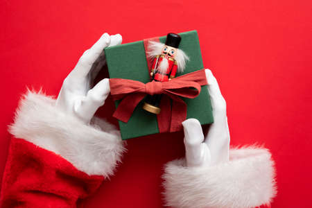 Santa Claus holding a wrapped gift box present against a red backgroundの写真素材