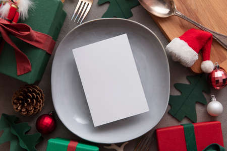Christmas meal blank menu. Blank paper menu on a dinner plate surrounded by festive decorationsの写真素材