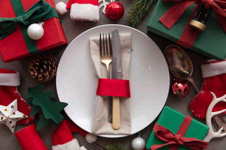 Festive Christmas meal background. Place setting with plate and cutlery surrounded by decorations...