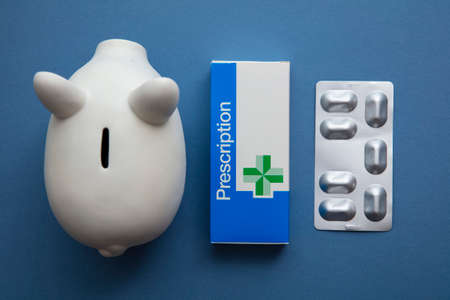 OXFORD, UK - May 2022: NHS medical prescription packaging with piggy bank. Healthcare cost conceptのeditorial素材