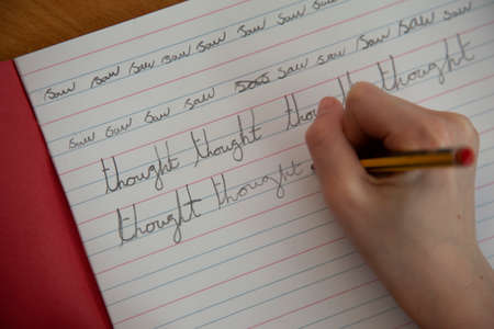 Close up of a childs hand practicing handwriting in schoolの写真素材