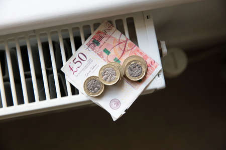 Cost of living crisis. Money on a home radiator heater. Rising cost of energy and billsの写真素材