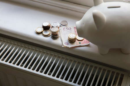 Cost of living crisis. Money on a home radiator heater. Rising cost of energy and billsの写真素材