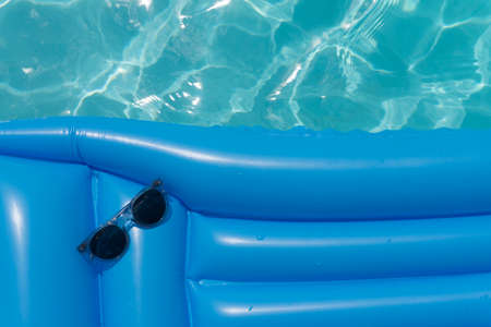 Sunglasses on a blue swimming pool float. Summer holiday backgroundの写真素材