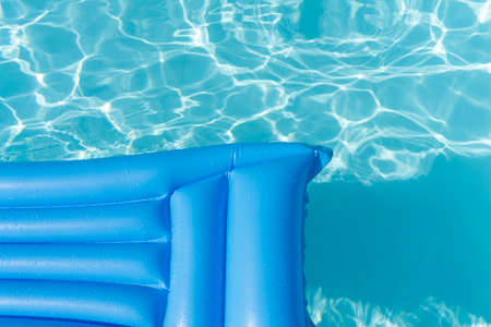 Bright blue summer pool lounger float on a rippled swimming poolの写真素材