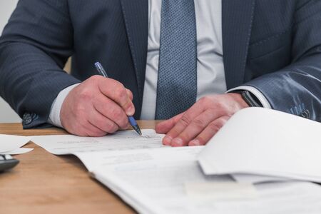 Businessman sitting at office desk signing contract with shallow focus on signature. Head of company sign contract investment professional document agreement in meeting room.の写真素材