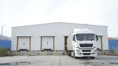 Semi-trailer truck standing at warehouse ramps for load or unload goods at dock logistics park. Truck in parking near warehouse.の写真素材