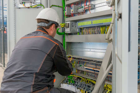 Electrician builder at work inspecting cabling connection of high voltage power electric line in...