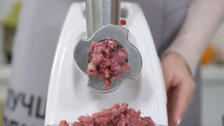 Making minced meat in an electric meat grinder from fresh beef at home. Pile of chopped meat....