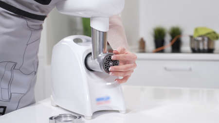 Female hands assembles meat grinder head for providing quality mince from meat. Electric mincer...