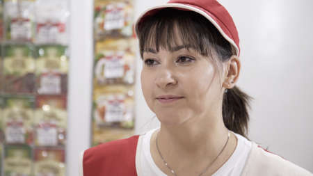 Portrait of smiling Caucasian female staff standing in grocery section of supermarket. Cheerful...