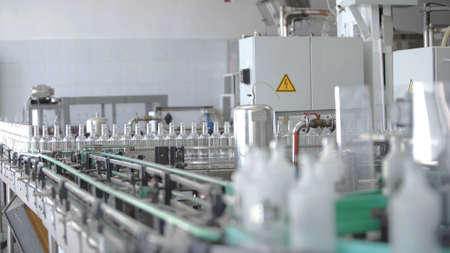 Factory for bottling alcoholic beverages. Working machine with several conveyor lines at time for production of vodka. Glass bottles in conveyor belt in distillery production line.の写真素材