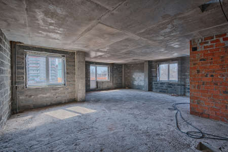 Apartment interior without finishing. Room in new building without repair, walls are not plastered. Repair works on construction site of residential apartment.の写真素材