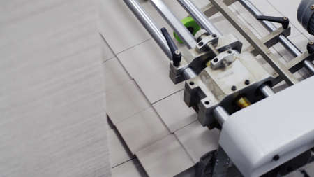 Conveyor line for the production of boxes. Machine cuts cardboard boxes from sheets of cardboard. Enterprise for the production package. Molds of corton boxes are collected in stackの写真素材