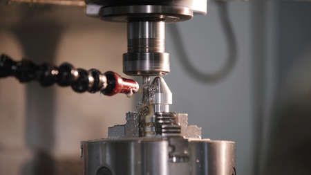 Produces metal detail in factory. Machine tools for metal working. A metal workpiece is machined by an electric machine. Cutting metal modern processing technology. Coolant and lubrication.の写真素材