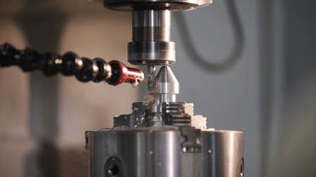 Produces metal detail in factory. Machine tools for metal working. A metal workpiece is machined by an electric machine. Cutting metal modern processing technology. Coolant and lubrication.の写真素材