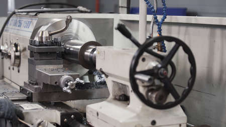 Turning lathe in action. Facing operation of metal blank on turning machine with cutting tool. Old turning lathe machine in turning workshop. Operator machining high precision mold part by cnc latheの写真素材