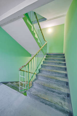 Building panel house interior with flight stairs and green walls. Precast concrete staircase. Flight of stairs. Flight of stairs are decorated building. Beautiful long staircase. Tile on floor.の写真素材