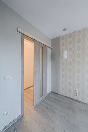 Sliding door in finishing apartment interior. Empty room in new building with repair, walls with wallpapers. Repair works on construction site of residential apartment.の写真素材