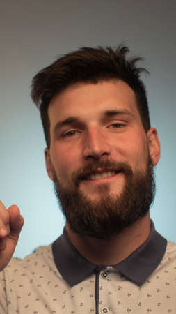 Portrait of bearded young male model rejoices coming weekends, dressed casually. Cheerful guy smiles...